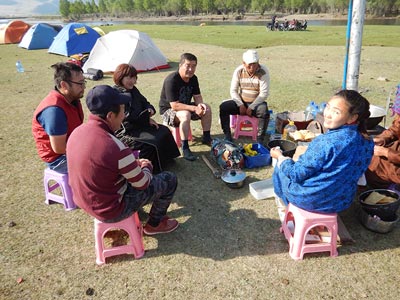Camp by the River Tuul - The crew making a delicious breakfast of fry bread, fresh cream and jam! Seated facing away - Driver Baagii, to his left Dr. Sukhbaatar Garam, Sarantuya ( co owner of Horse Trek Mongolia and Camp Manager of the Gobi Gallop) Driver Khloyaa, guide Batsumber, Cook Tuya ( mostly missing) and assistant cook Ari. All the riders in the background.