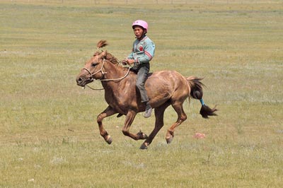 A child jockey at full gallop during a Naadam race. Many children ride these 28 -32 kilometre races without saddle and often without shoes.