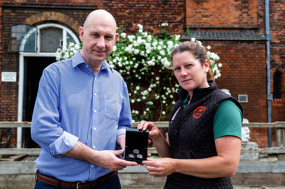 Stephen Lee, managing director of Bradford Exchange presents to Theresa Barrett, stable manager of The Horse Rangers Association, during the launch of the gold quarter sovereign to feature the portrait of the Queen on horseback, released by Bradford Exchange at the Horse Rangers Association, Royal Mews, Surrey. Photo credit: Steven Paston/Press Association.