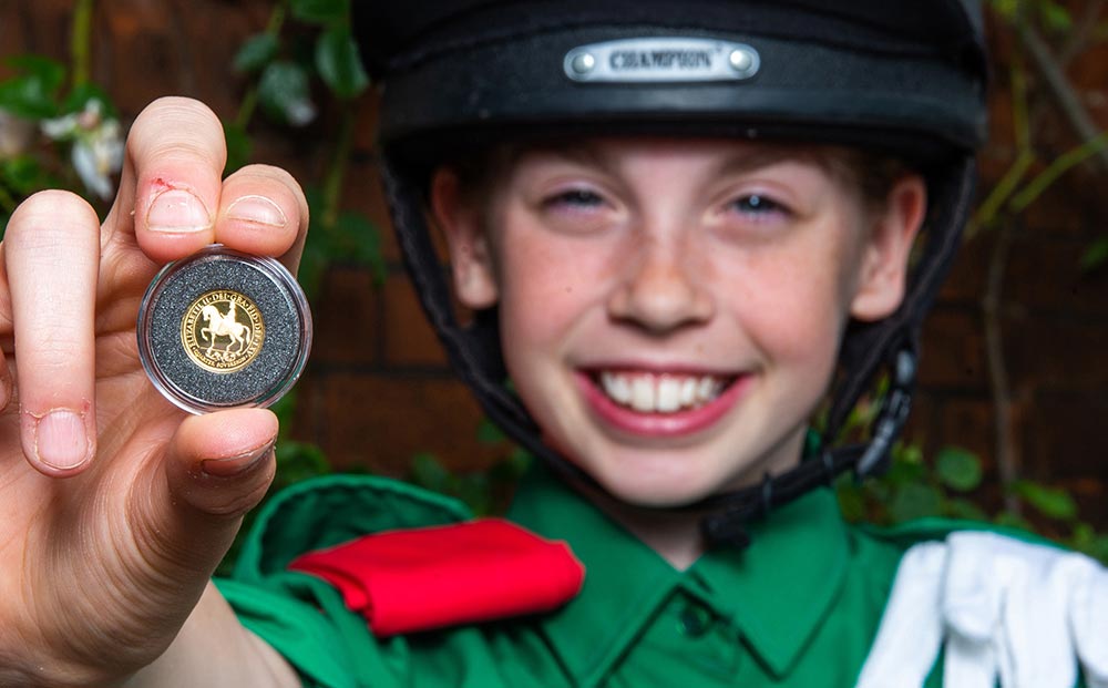Abi Evans holds a gold quarter sovereign which features a portrait of Queen Elizabeth II on horseback during the launch of the coin with the Horse Rangers Association, at the Royal Mews in Hampton Court, Surrey. Photo credit: Steven Paston/Press Association.