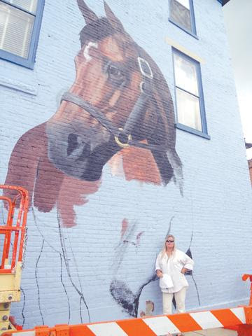 Pamela Bliss working on mural of Single G at U.S. Bank building photo courtesy of News Examiner
